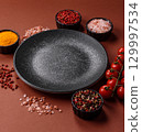Empty round black plate for food, kitchen utensils on dining table. Empty plate 129997534