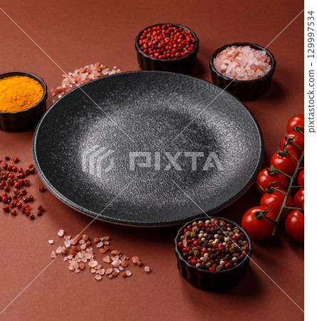 Empty round black plate for food, kitchen utensils on dining table. Empty plate 129997534