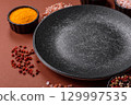 Empty round black plate for food, kitchen utensils on dining table. Empty plate 129997535