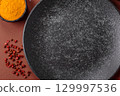 Empty round black plate for food, kitchen utensils on dining table. Empty plate 129997536