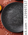 Empty round black plate for food, kitchen utensils on dining table. Empty plate 129997537