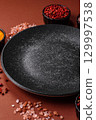 Empty round black plate for food, kitchen utensils on dining table. Empty plate 129997538