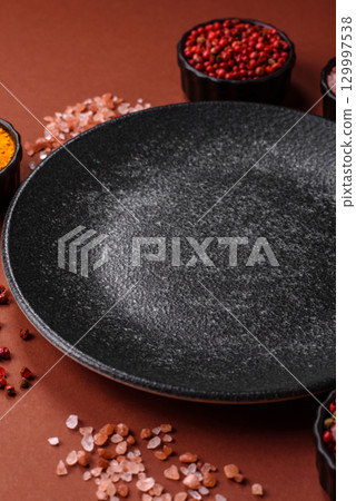 Empty round black plate for food, kitchen utensils on dining table. Empty plate 129997538