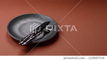Empty round black plate for food, kitchen utensils on dining table. Empty plate 129997544