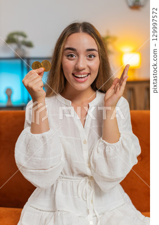 Portrait of happy young woman holding two gold BTC coins at home successful developer programmer Portrait of happy young woman holding two gold BTC coins at home successful developer programmer 129997572