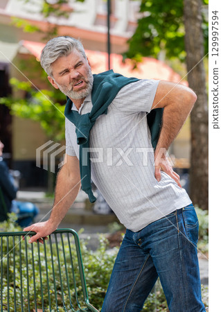 Mature man suffers from back pain in lower part of spine unbearable spasm torn muscles pinched nerve 129997594