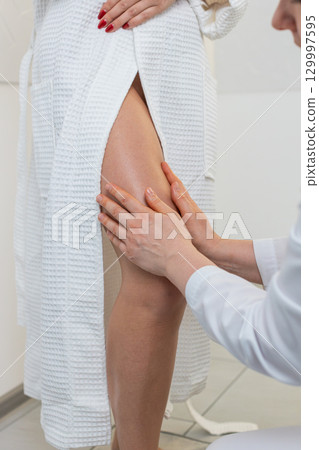 Experienced therapist doctor making woman relaxing spa anti-cellulite legs treatment hands massage Experienced therapist doctor making woman relaxing spa anti-cellulite legs treatment hands massage 129997595
