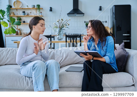 Female social worker working at home with teenage girl Female social worker working at home with teenage girl 129997709