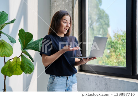 Young teenage girl using laptop for video chat conference standing at home Young teenage girl using laptop for video chat conference standing at home 129997710