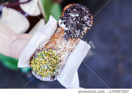 Young Italian woman holding cannoli (traditional Sicilian pastry) 129997897