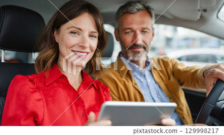 Smiling mature couple using digital tablet while sitting inside car 129998217