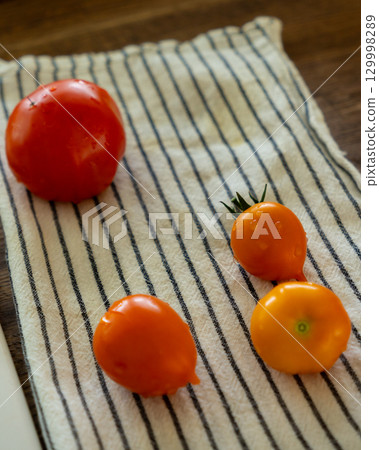 Close-up of four small tomatoes on a cloth napkin in the kitchen.  129998289
