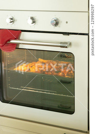 Pizza with pepperoni and sausage cheese is baked in the oven in kitchen or in family restaurant.  129998297