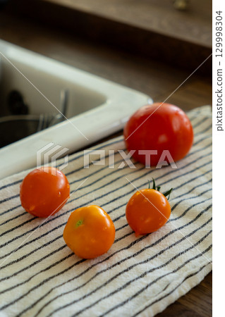 Close-up of four small tomatoes on a cloth napkin in the kitchen.  129998304