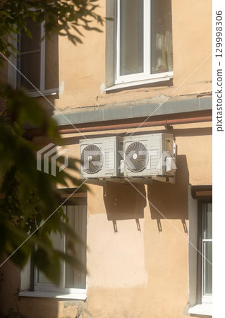 Air conditioners are installed on facade of building. device for comfortable living in hot weather. 129998306