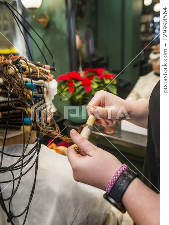 a young girl is getting her hair curled with curlers 129998564