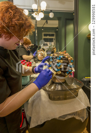 a young girl is getting her hair curled with curlers 129998581