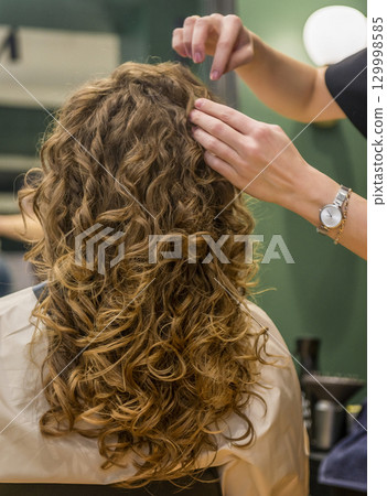 Girl in a beauty salon after styling with a gorgeous hairdo 129998585