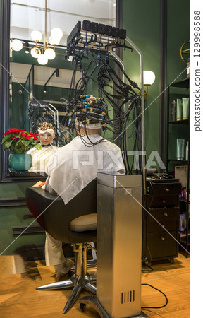 a young girl is getting her hair curled with curlers 129998588