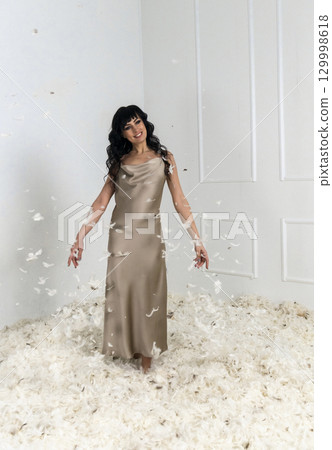 beautiful slim girl throws white feathers 129998618