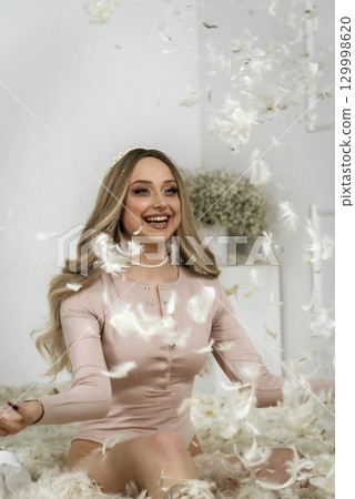 young beautiful blonde girl among feathers young beautiful blonde girl among feathers 129998620