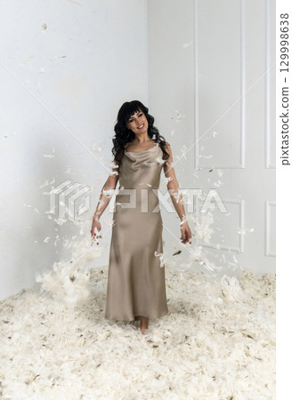 beautiful slender girl white feathers are flying around her 129998638