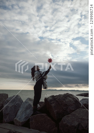 a beautiful young girl with long dark hair stands on the seashore the wind blow a beautiful young girl with long dark hair stands on the seashore the wind blow 129998714