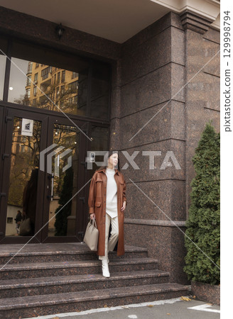 elegant woman over 40 exiting building with laptop bag 129998794