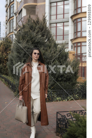 elegant woman over 40 exiting building with laptop bag elegant woman over 40 exiting building with laptop bag 129998809