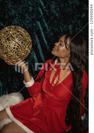 Dark-skinned beautiful girl in red New Year's dress with gold decor 129998844