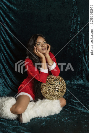 Dark-skinned beautiful girl in red New Year's dress with gold decor 129998845
