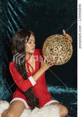 Dark-skinned beautiful girl in red New Year's dress with gold decor 129998846