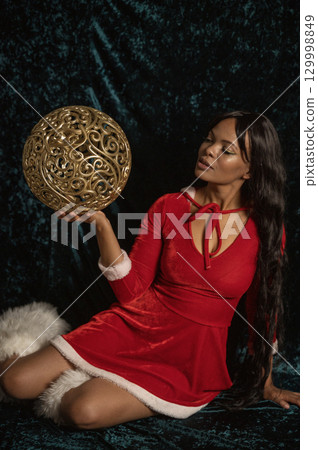 Dark-skinned beautiful girl in red New Year's dress with gold decor Dark-skinned beautiful girl in red New Year's dress with gold decor 129998849