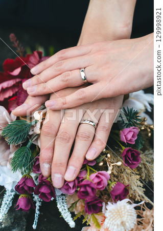 雙手緊握，捧著結婚戒指和花束 129998921