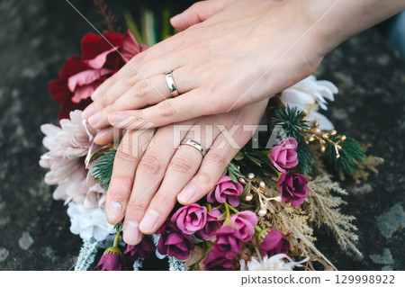 雙手緊握，捧著結婚戒指和花束 129998922