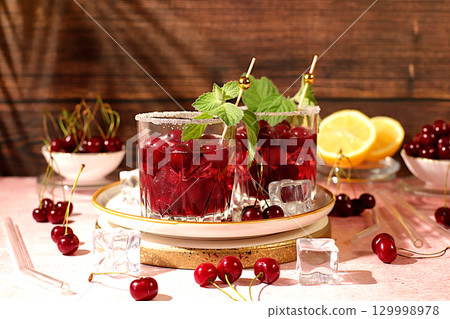 Mojito with cherry, mint, ice with tequila, vodka or soda water on elegant background, minimalist concept for bar, soft and alcoholic drink for weight loss, advertising banner for cafe. Mojito with cherry, mint, ice with tequila, vodka or soda water on elegant background, minimalist concept for bar, soft and alcoholic drink for weight loss, advertising banner for cafe. 129998978