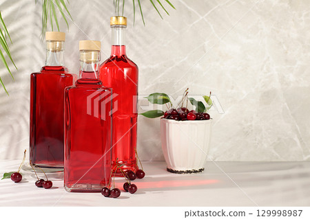 Homemade strong cherry cider in bottles and glasses on elegant background, still life with alcoholic drinks and fresh cherries, home winemaking concept, minimalist banner for bar, 129998987