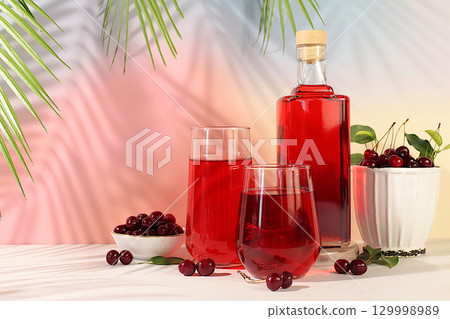 Homemade strong cherry cider in bottles and glasses on elegant background, still life with alcoholic drinks and fresh cherries, home winemaking concept, minimalist banner for bar Homemade strong cherry cider in bottles and glasses on elegant background, still life with alcoholic drinks and fresh cherries, home winemaking concept, minimalist banner for bar 129998989
