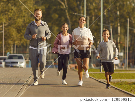 Active parents with their children do sports by running together in city park in morning. Active parents with their children do sports by running together in city park in morning. 129999813