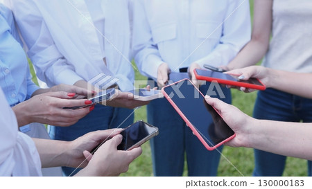 A diverse group of friends happily showing their smartphones while enjoying modern technology together outdoors 130000183