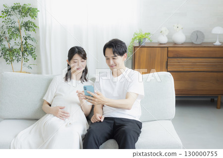 客廳裡的孕婦,夫婦,智慧型手機 客廳裡的孕婦,夫婦,智慧型手機 130000755