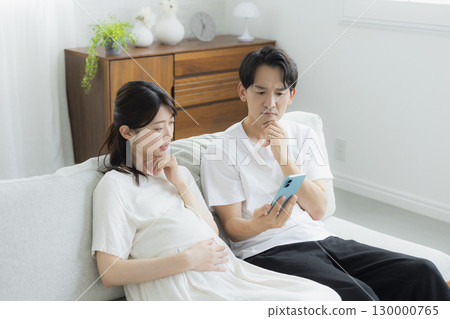 Pregnant woman in the living room, couple, smartphone 130000765