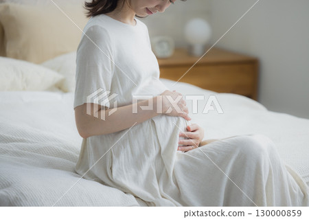 孕婦坐在臥室的床上 孕婦坐在臥室的床上 130000859
