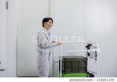 A man in work clothes pushing a cart in a warehouse 130001146