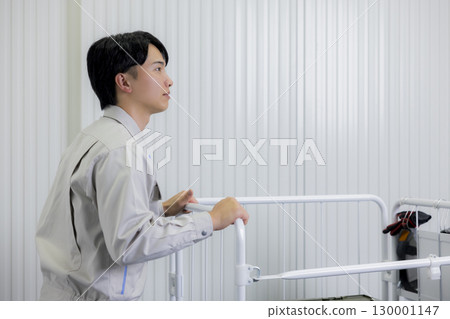 A man in work clothes pushing a cart in a warehouse 130001147