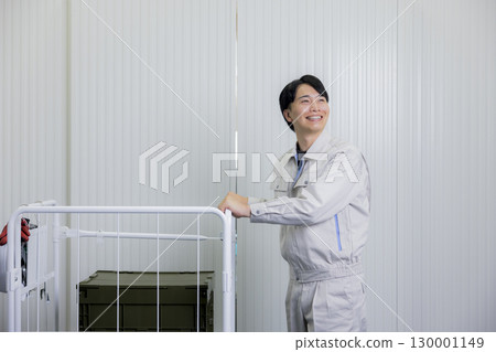 一名身穿工作服的男子在倉庫裡推著手推車 130001149