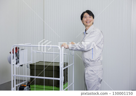 一名身穿工作服的男子在倉庫裡推著手推車 130001150