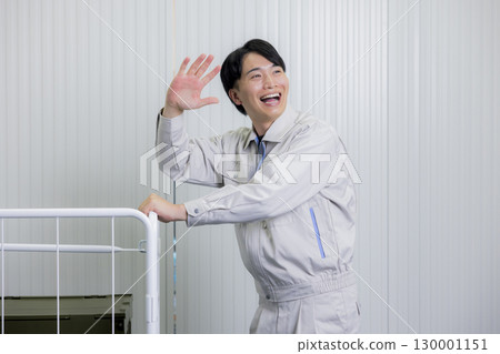 A man in work clothes pushing a cart in a warehouse 130001151