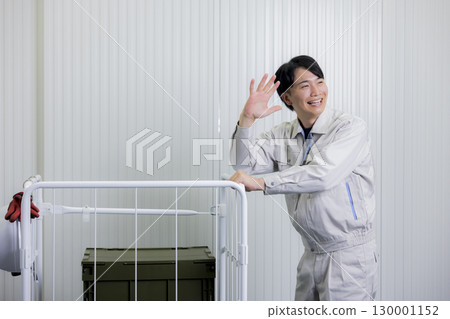 一名身穿工作服的男子在倉庫裡推著手推車 130001152