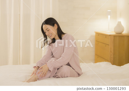 A woman sitting on a bed A woman sitting on a bed 130001293